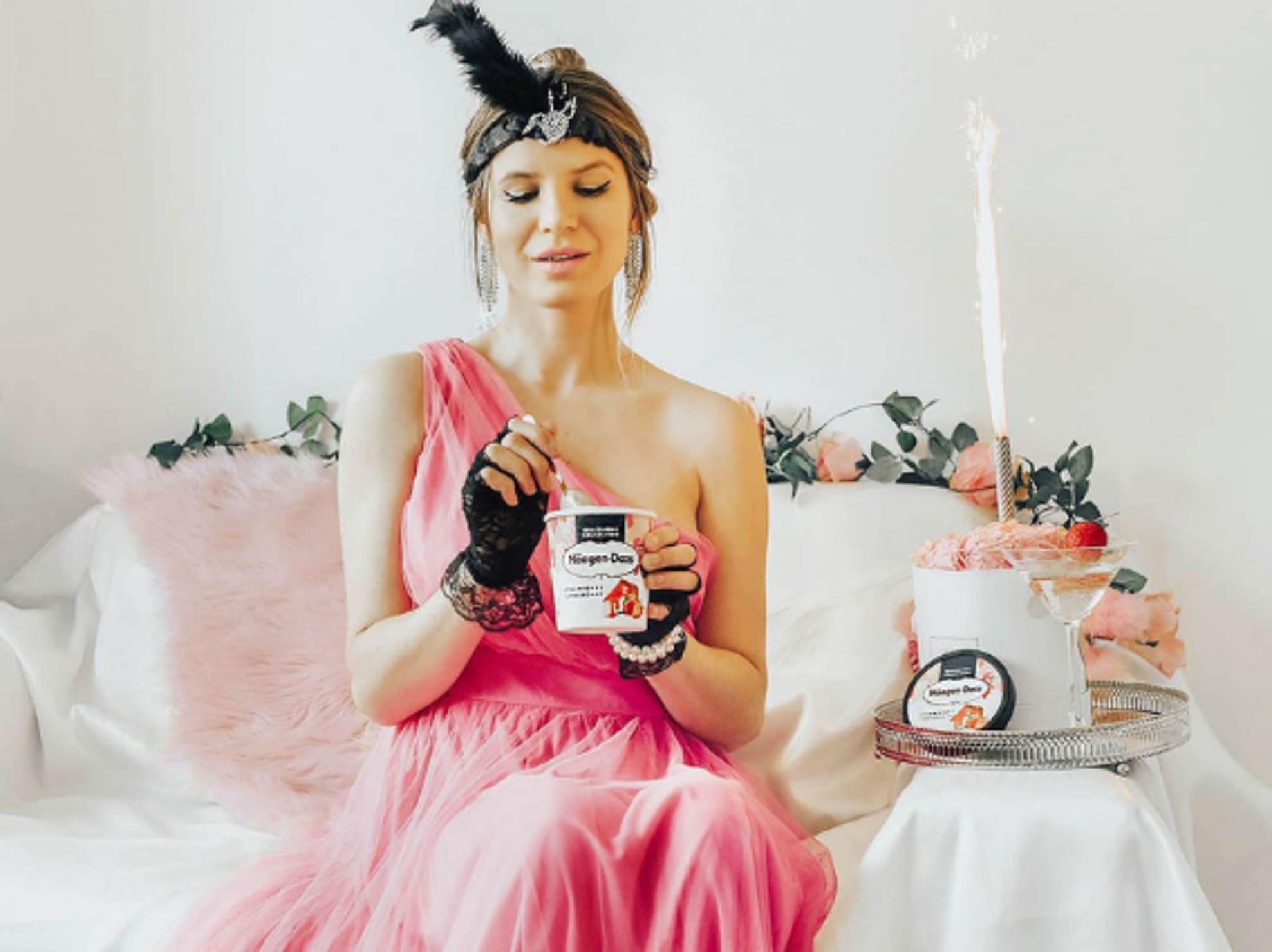 Woman dressed up sitting on couch eating Haagen Dazs ice cream